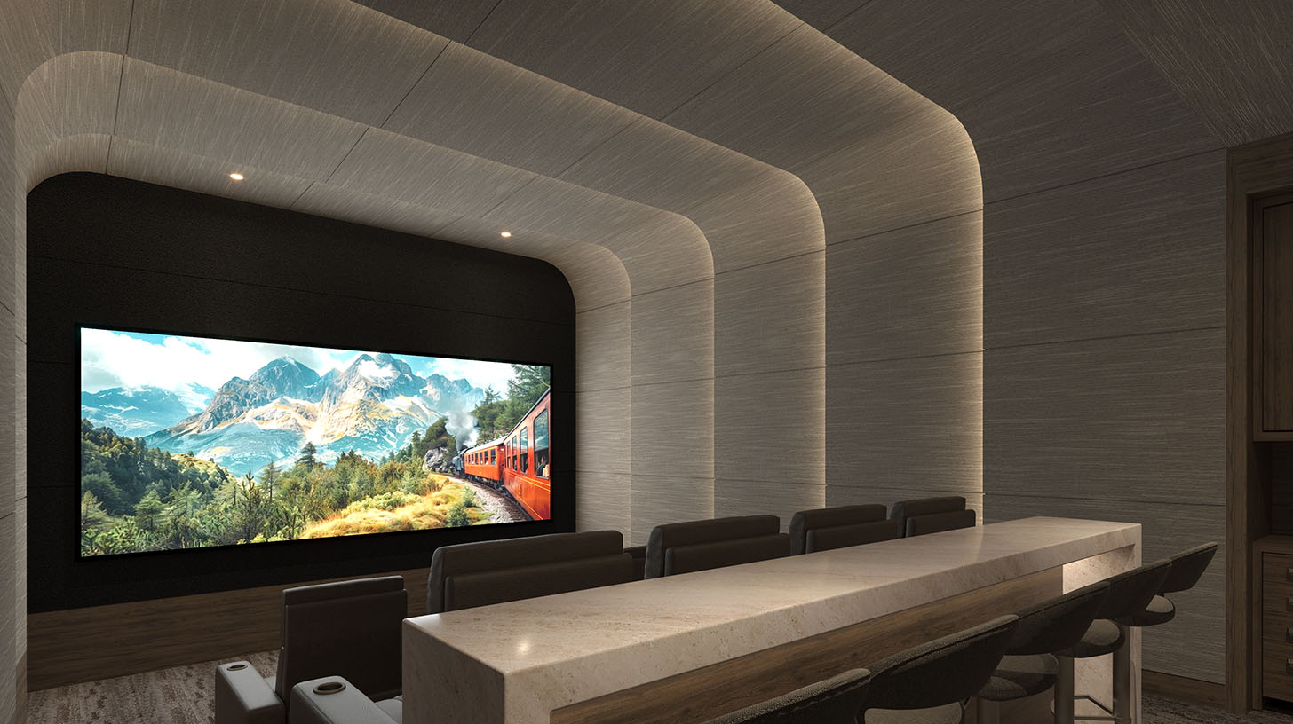 Modern luxury home theater with a sleek, layered ceiling design featuring soft, indirect lighting along curved lines. The theater space includes comfortable leather seating arranged in rows, facing a large, high-definition screen displaying a scenic mountain landscape with a red train moving through. In the foreground, a long, polished stone bar counter with barstool seating adds sophistication, blending functional design with aesthetics for a refined viewing experience.